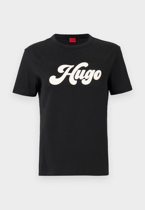 Maglietta in cotone nera a maniche corte con un grande logo bianco "Hugo" in un font stilizzato al centro della parte anteriore.