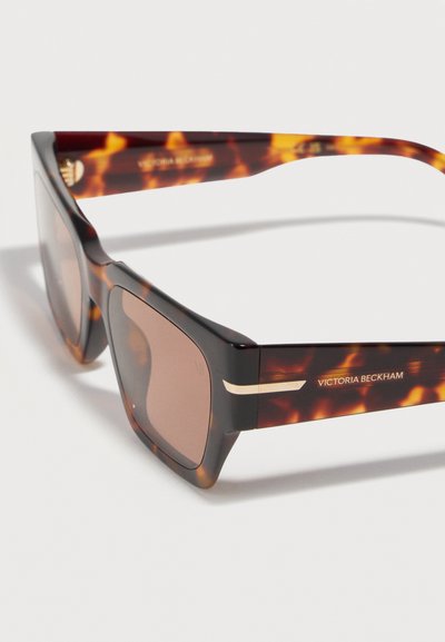 Ορθογώνια γυαλιά ηλίου σε χρώμα χελώνας με καφέ φακούς, χρυσές λεπτομέρειες στα πλαϊνά και το λογότυπο "Victoria Beckham" στη μία πλευρά.