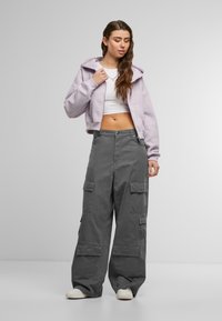 Lys lavendel cropped hoodie, hvid tanktop og løse grå cargo bukser med flere lommer, stylet med hvide sneakers.
