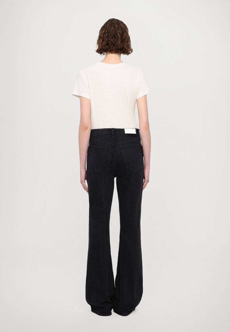 Jeans neri a gamba larga con texture rigata verticale, dotati di vita alta e tasche posteriori. Abbinati a un top a maniche corte di colore chiaro.