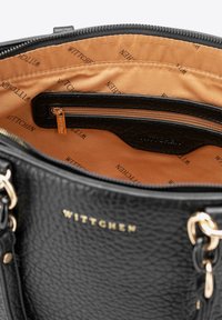 Czarna torebka z teksturowanej skóry z złotymi akcentami, z beżowym wnętrzem, zapinana na zamek kieszonka i nadrukowane logo.