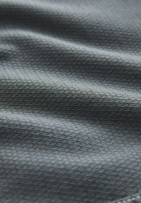 Tessuto grigio scuro strutturato che mostra un motivo geometrico di piccoli diamanti, con lievi ondulazioni che indicano morbidezza e flessibilità.