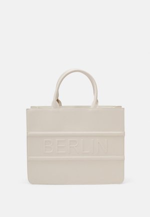Beżowa torba typu tote o gładkiej fakturze z tłoczonym napisem "BERLIN" na przodzie. Posiada dwa solidne uchwyty i prosty, przemyślany design.