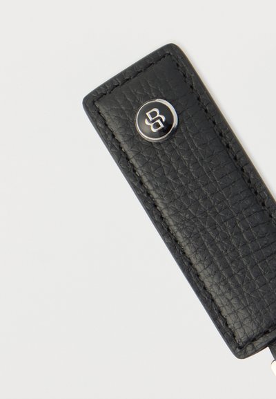 Porte-clés en cuir noir texturé avec un logo métallique rond présentant un design entrelacé "DS".