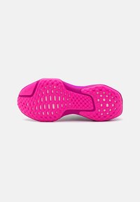 Lys pink skosål med struktureret gummimønster, der har hexagonale og cirkulære greb, samt en glat hvid mellemsål.