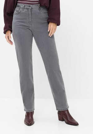Person iført grå jeans med høj talje, bordeaux ankelstøvler med hæl og en bordeaux langærmet top med en stribet skjorte under.