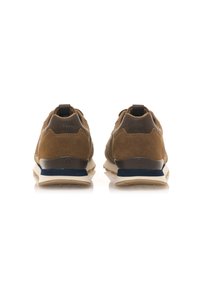 Zapatillas de ante marrón con una suela beige y acentos azul oscuro. Cuentan con un cuello acolchado en el tobillo y detalles del logo en el talón.