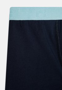 Námornícke modré boxerky s pásom s svetlomodrým logom, vyrobené z mäkkej látky a s priliehavým strihom. Pozoruhodné švy po stranách.