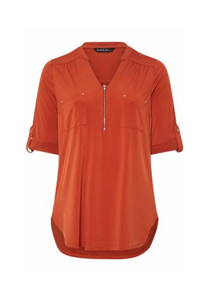 Rode blouse met korte mouwen, een V-hals en een rits aan de voorkant. Beschikt over twee borstzakken en opgekrulde mouwmanchetten. Gladde, lichte stof.