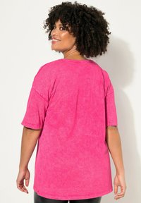 Übergroßes pinkes Baumwoll-T-Shirt mit Mineralwascheffekt, runden Ausschnitt und kurzen Ärmeln. Glatte Textur und lockerer Schnitt.