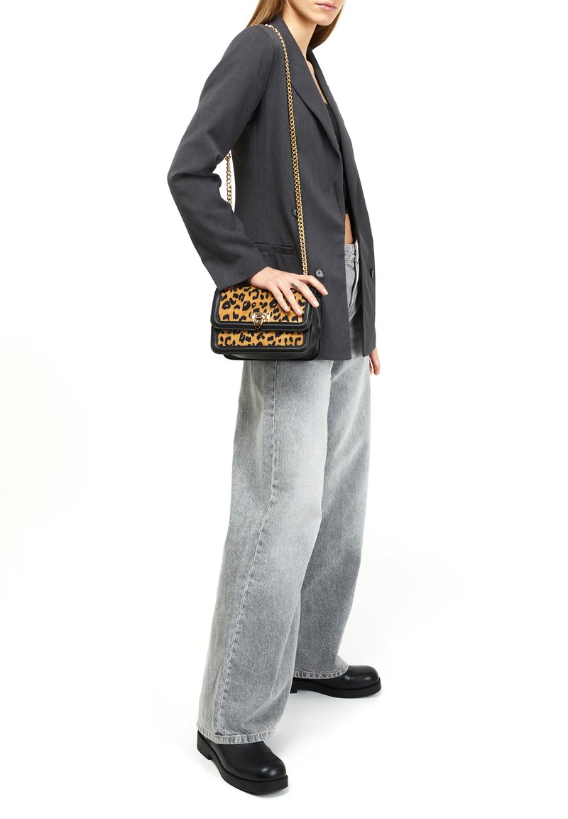 Svart och beige leopardmönstrad axelväska med ett guldkedjesnöre, har en klaffstängning och svarta detaljer. Bärs tillsammans med grå vida jeans.