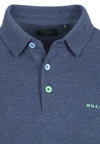 Navyblauwe poloshirt van een gestructureerde stof, met twee lichtblauwe knopen, één groene knop en groene logoborduring op de borst.