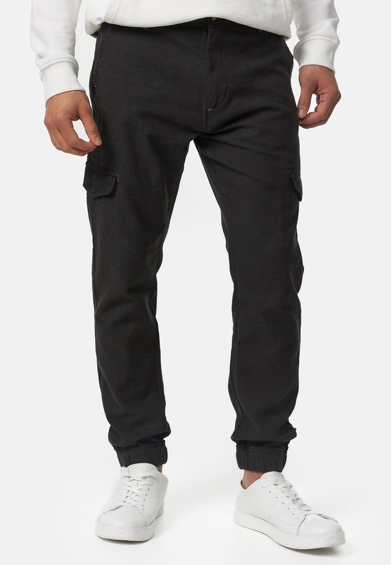 Pantalones cargo negros con puños ajustados, que cuentan con bolsillos laterales y un diseño clásico. El material es texturizado, con un acabado duradero.