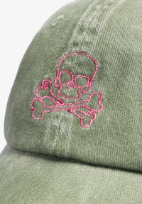 Gorra de béisbol de tela verde con diseño de calavera y tibias cruzadas bordado en rosa en el panel frontal.