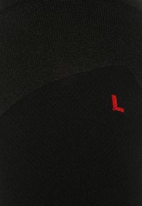 Calzino nero con un design a maglia testurizzata, featuring un piccolo "L" rosso alla caviglia. Il materiale sembra morbido ed elastico.