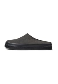 Zapatos slip-on de ante gris con punta redondeada, superficie texturizada y suela de goma negra con un patrón estriado.