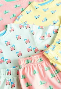 Zestaw odzieży loungewear wykonany z bawełny, w pastelowych kolorach: różowym, zielonym i żółtym, z powtarzającymi się wzorami ciężarówek. W skład zestawu wchodzą bluza i szorty.