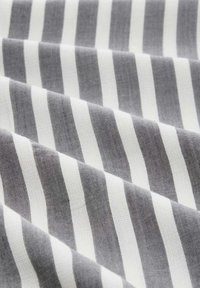 Tissu rayé gris et blanc avec un tissage texturé, présentant des lignes diagonales s'entrecroisant dans un arrangement lisse et drapé.