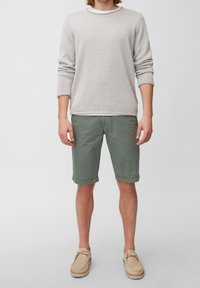 Vaaleanharmaa neuletyyppinen paita, vihreät shortsit ja beiget kengät. Paidassa on tekstuurimäinen kuvio; shortseissa on suoraviivainen leikkaus ja näkyvät saumat.