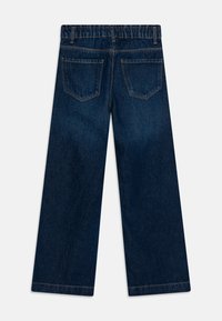 Pantalones de mezclilla anchos de color azul oscuro con cintura elástica y dos bolsillos traseros. La tela tiene una textura suave y está ligeramente desgastada.