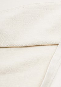 Off-white, strukturierter Stoff mit gewebtem Muster; verfügt über eine glatte Oberkante und einen gesäumten Saum. Geeignet für verschiedene Bekleidungsanwendungen.