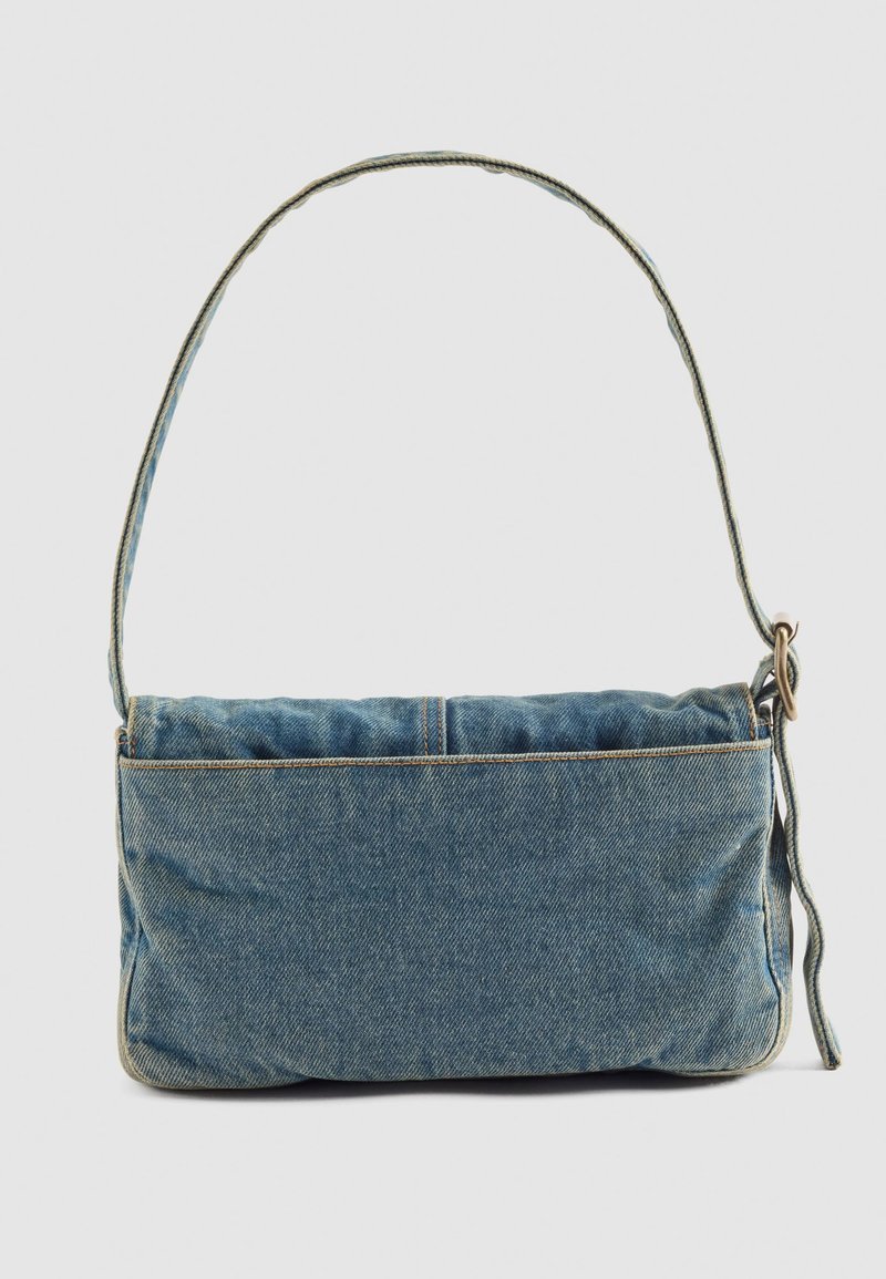 Piccola borsa a tracolla rettangolare in denim con lungo manico e fibbia in ottone, esposta su uno sfondo chiaro e semplice.