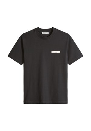 Black short-sleeve crewneck t-shirt with a small rectangular white patch featuring cursive text on the left chest.