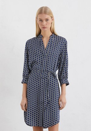 Abito blu navy con un motivo geometrico bianco, collo a camicia, maniche lunghe e vita svasata con una cintura abbinata. Tessuto morbido.