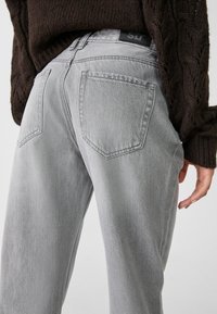 Harmaat denim-farkut suoran lahkeen istuvuudella, joissa on kaksi takataskua ja musta vyötärölabel. Kangas on pehmeää. 
