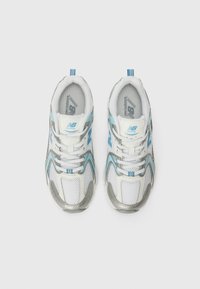 Tenis brancos para corrida com detalhes em prata, pormenores em azul claro, parte superior em malha, fecho com atacadores e colarinho almofadado para conforto.