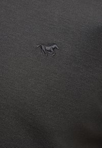 Tissu noir texturé avec un petit emblème brodé d'un cheval gris foncé centré sur la surface.