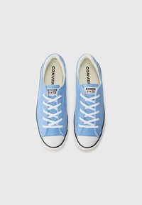 Light blue canvas sneakers with white laces, black rubber sole and toe cap. Logo patch on tongue reads "Converse All Star." Smooth texture.