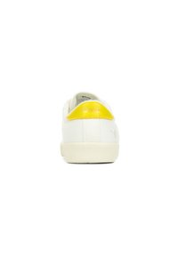 Zapatillas de lona blancas con un acento amarillo en el talón. El diseño incluye una suela texturizada y un sutil logo en la parte posterior.