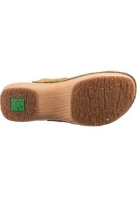 Grön och brun sandal sula med en texturerad gummibotten, trä-mellansula och en groda-logotyp. Har rundade kanter och förstärkt vrist.