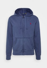 Sudadera con capucha azul marino con cremallera, hecha de algodón, con capucha ajustable con cordón, bolsillos frontales y un pequeño logo rojo en el pecho izquierdo. Textura suave.