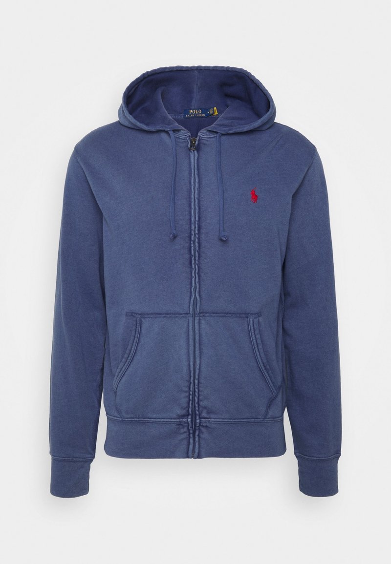 Sudadera con capucha azul marino con cremallera, hecha de algodón, con capucha ajustable con cordón, bolsillos frontales y un pequeño logo rojo en el pecho izquierdo. Textura suave.