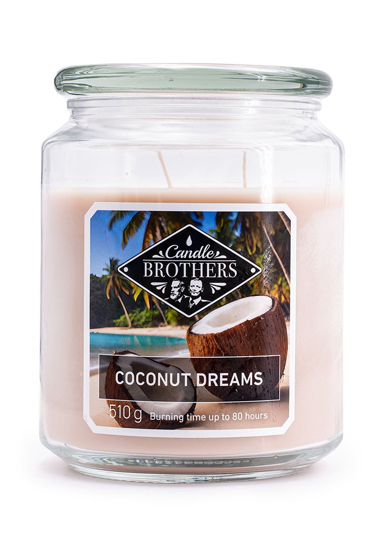 Coconut Dreams kaars in een heldere glazen pot, lichtroze was, wit etiket met een kokosnootafbeelding en zwart logo. 510g, brandtijd van 80 uur.