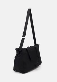 Černá nylonová kabelka přes rameno s nastavitelným popruhem, zipem na vrchu a horními držadly. Disponuje hladkým povrchem a minimalistickým designem.