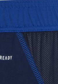Marineblaue Sportshorts mit einem blauen elastischen Bund, versehen mit genähten Nähten und einem Netzpaneel für Atmungsaktivität, mit der Aufschrift "READY" in Weiß.