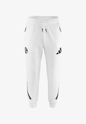 Białe spodnie sportowe z elastycznym pasem i sznurkiem, czarne logo Adidas na prawej udzie, czarne okrągłe logo na lewym udzie oraz czarne paski po bokach.