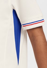 Witte T-shirt met korte mouwen met blauwe zijpanelen, geribbelde blauwe, rode en witte streepaccenten op de manchetten en een gestructureerde stof.