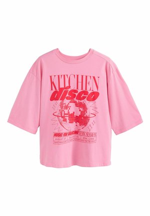 Oversized pinkes T-Shirt mit rotem Text "KITCHEN disco" und einer Discokugel-Grafik, die eine Tanzveranstaltung am 27. August von 21 bis 2 Uhr bewirbt.