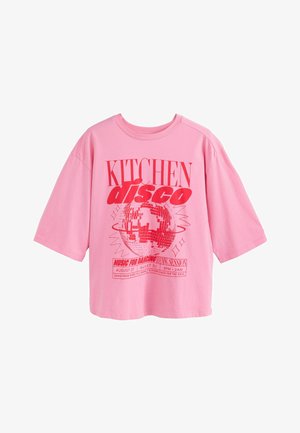 Oversized pinkes T-Shirt mit rotem Text "KITCHEN disco" und einer Discokugel-Grafik, die eine Tanzveranstaltung am 27. August von 21 bis 2 Uhr bewirbt.
