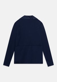 Navy blue long-sleeve top with a collar, featuring a smooth texture and a horizontal seam across the back. Simple design with no visible patterns.