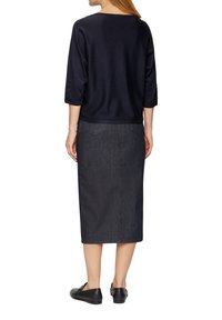 Granatowy sweter z dzianiny z rękawami 3/4 w połączeniu z ciemnoniebieską spódnicą midi z denimu. Spódnica posiada tylne kieszenie i prosty krój.