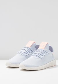 Ljusblå nät-sneakers med en texturerad ovandel, platta snören och en rosa detalj på hälfliken. Har en mönstrad vit sula.