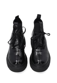 Černé kotníkové boty vyrobené z lesklé lakované kůže s kulatou špičkou, silnou černou gumovou podrážkou a černými šněrovadly na zapínání.