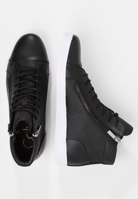 Černé vysoké tenisky s koženým svrškem, texturovaným panelem, bílou podrážkou a stříbrným zipem na boku. Šněrování vpředu.