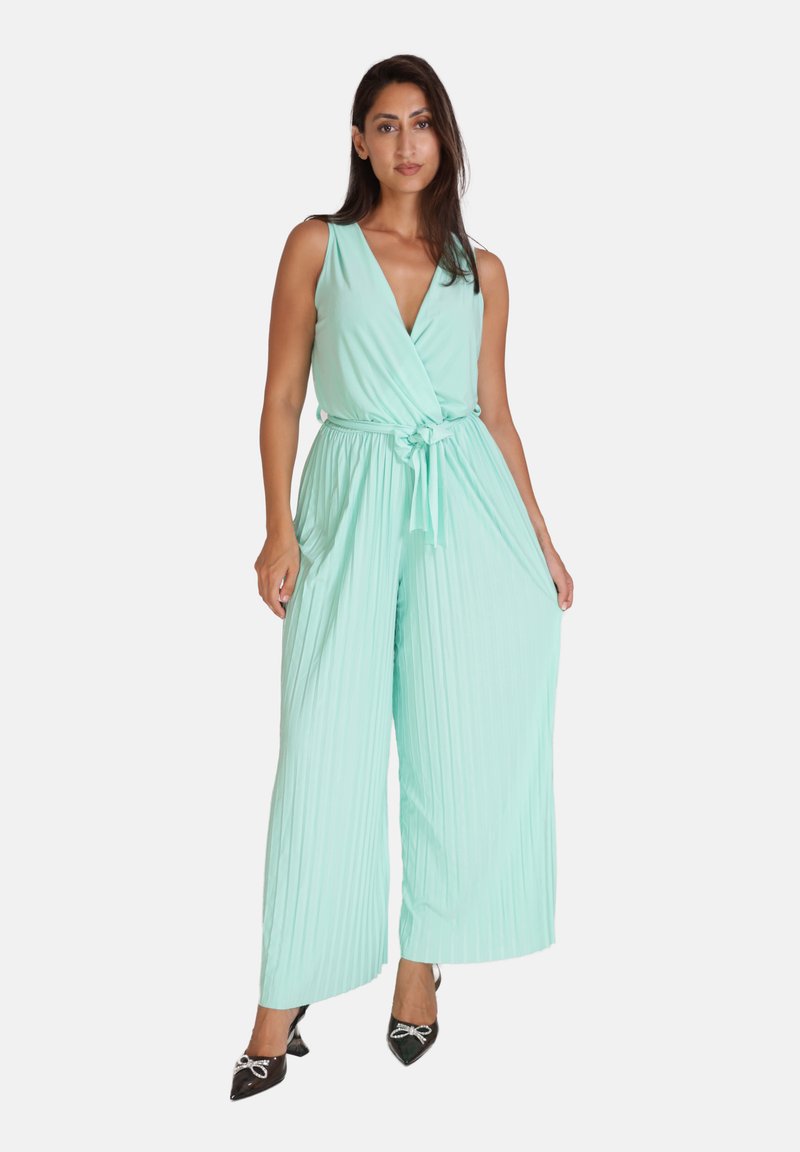 En myntegrøn, ærmeløs jumpsuit med v-hals og knyttet talje, der har plisseret vidde ved benene og en glat overflade.