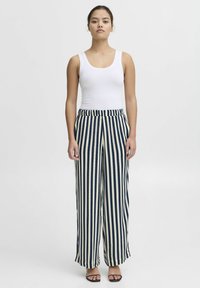 Striped wide-leg pants in navy and cream, featuring a high waist and elastic waistband. Paired with a fitted white tank top.
